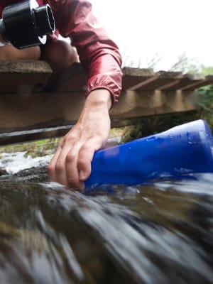 a female hiker filling up her water bottle to showcase portable water filter rv options